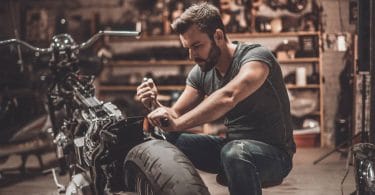 Une personne en train de réparer lui même sa moto dans le garage de sa maison