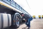 Un chauffeur poids lourd en train d'inspecter les pneus de son camion