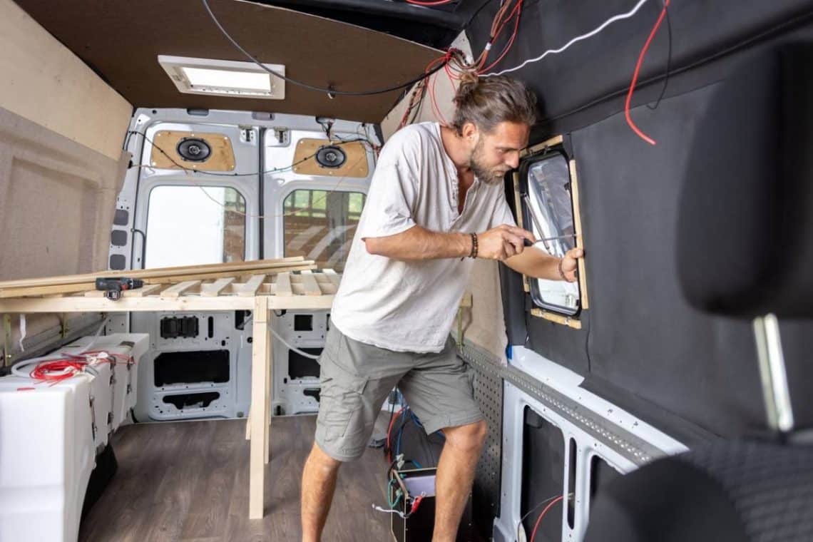Un jeune homme qui bricole sur l'amménagement de son van