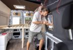 Un jeune homme qui bricole sur l'amménagement de son van