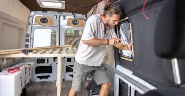 Un jeune homme qui bricole sur l'amménagement de son van