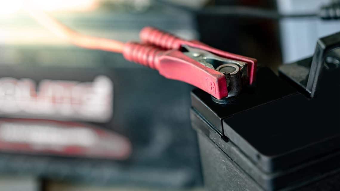 Une batterie de voiture à plat que se fait recharger par un booster de batterie