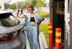 Une femme en train de recharger sa voiture électrique à une borne de recharge d'un supermarché