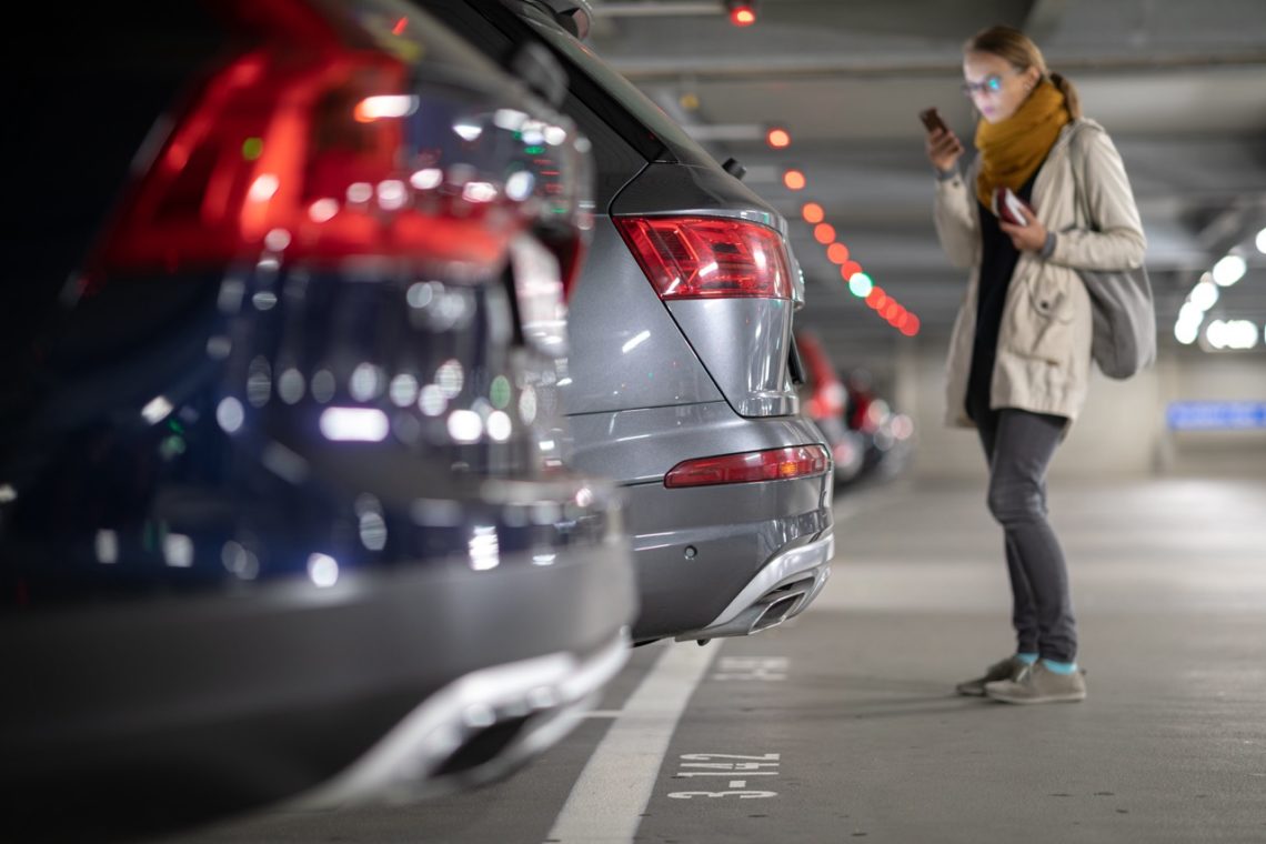 Une femme qui a garé sa voiture sur dans un parking d'aéroport pour partir en vacance