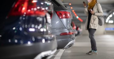 Une femme qui a garé sa voiture sur dans un parking d'aéroport pour partir en vacance