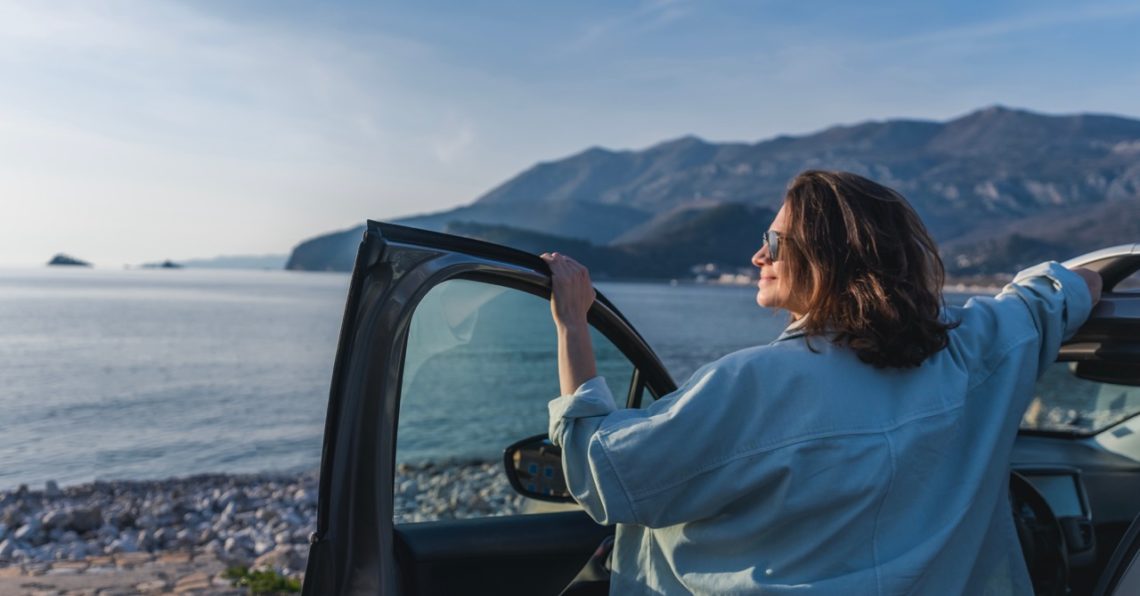 Une femme en vacance avec sa voiture, au bord de la mer
