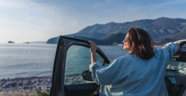 Une femme en vacance avec sa voiture, au bord de la mer